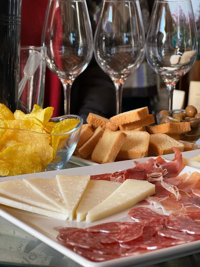 A delicious spread of Spanish tapas featuring cheese, cured meats, bread, and chips, ideal for wine tasting.